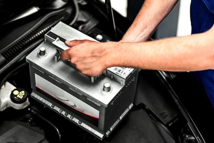 Auto electrician performing diagnostic testing on vehicle electrical system